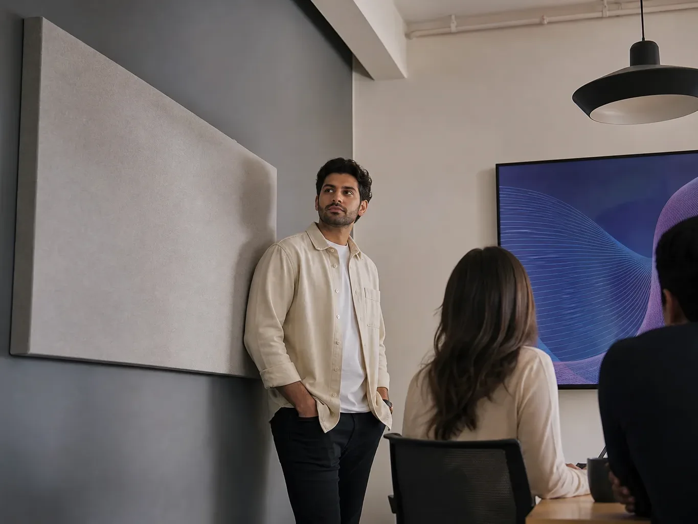 A fabric-wrapped acoustic panel mounted on a wall beside a meeting area